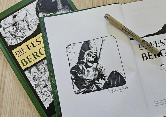 Aufgeschlagenes Exemplar vom Buch Die Festung des Bergkönigs mit einer Tuscheskizze auf einer Innenseite.