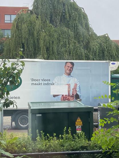 Sligro teuck met op de zijkant een foto van een slager met een stuk dood dier, tekst erbij luidt 'stoer vlees maakt indruk'
