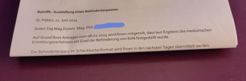 Ausschnitt eines Briefes auf einem lila Tisch mit dem Betreff "Ausstellung eines Behindertenpasses", in dem ebendies mitgeteilt wird.