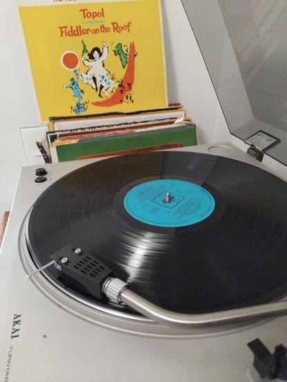 LP playing in front of front cover of album.
Cover has a young woman dancing, a fiddler on a roof.
And a green rooster.