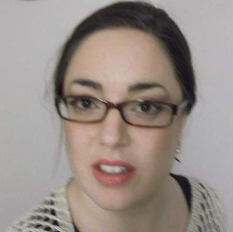 Color; square: Selfie headshot of a Caucasian woman wearing glasses and makeup.