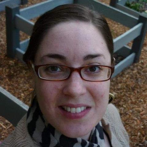 Color; square: Selfie headshot of a Caucasian woman wearing glasses and no makeup, showing a blemished complexion.