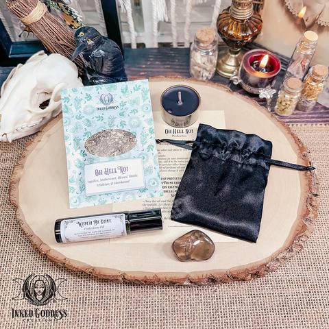The contents of our exclusive "Oh Hell No! Spell Kit" product are arranged on a raw wood slice. They include a black Oh Hell No! tealight candle; a pouch of Oh Hello No! herbs, including angelica, motherwort, blessed thistle, mistletoe, and horehound; a roller ball vial of our exclusive Witch Be Gone Protection Oil; a tumbled smoky quartz gemstone; spell instructions; and a small black satin drawstring bag. Presented by Inked Goddess Creations.