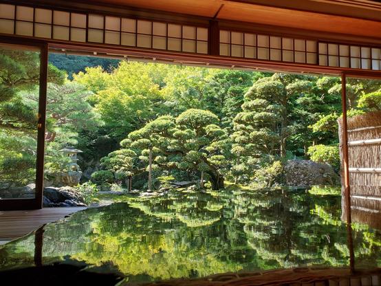 The garden at Omuro-tei reflected on a polished table.