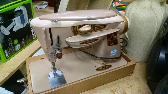 Dun colored antique Singer sewing machine, the body having sweeping, curved, streamlined lines, like something from "The Jetsons" or an old science fiction book cover.