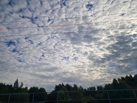 Sun poking through clouds seen from a train window. 