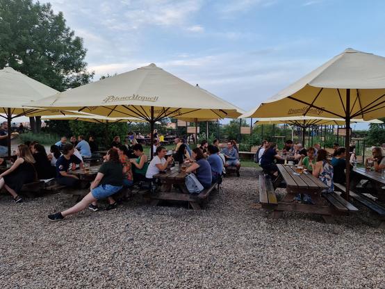 People sitting at picnic benches in a beer garden. 