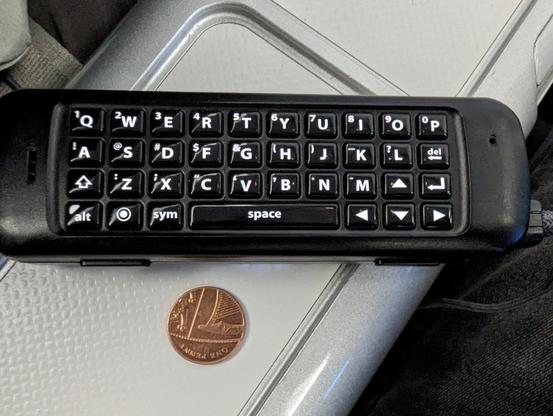 A small black keyboard next to a coin for scale