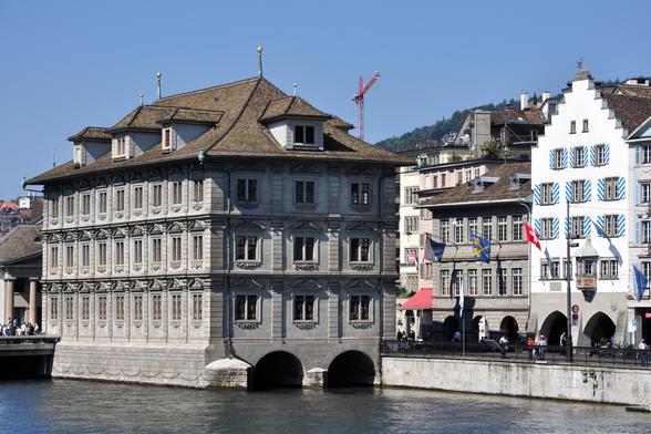 Foto des Rathauses in Zürich an der Limmat, die unter ihm hindurchfliesst. Quelle: Roland zh, Wikipedia