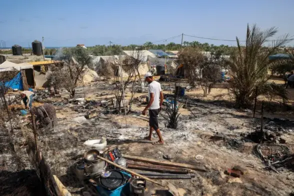 Palestinians look for salvageable items from the remains of tents burned down by an Israeli raid in the al-Mawasi area, northwest of the city of Rafah on June 29, 2024 [Eyad Baba/ AFP]