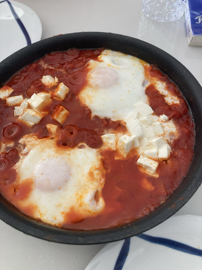 A pan of Shakshuka, a tomato Paprika sauce with two eggs on top. The yolk of the egg is covered with egg white.
