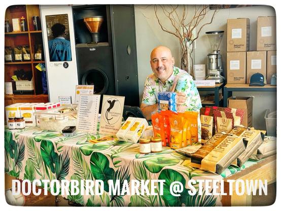 Zane from DoctorBird Market sitting at a Steeltown table with his products. 