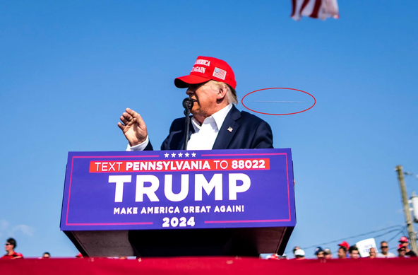 Picture of Former President and Candidate Trump speaking at an outdoor podium with the shockwave from a passing assassin's bullet circled in red.