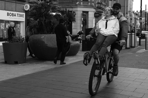 Two people on the high street on a bicycle