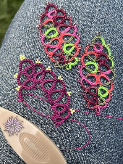 Tatted lace leaves including an unfinished leaf with beads added.