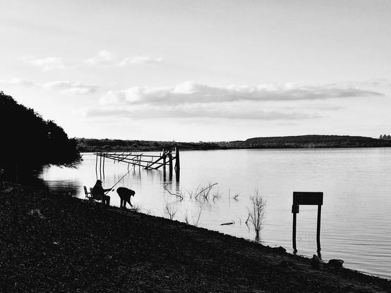 Two old guys fishing in the river. A few meters behind them there's a ruined dock.
The Pic is in grayscale, and the fishermen standout in contrast to the river calm water.