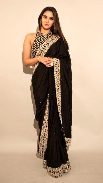 Discover the allure of Nikita Dutta in Ashutosh Joshi's black and gold saree. The luxurious fabric and intricate designs create a stunning visual appeal. Nikita's poised appearance adds a touch of modern elegance to this traditional attire, making it a must-see for fashion lovers.