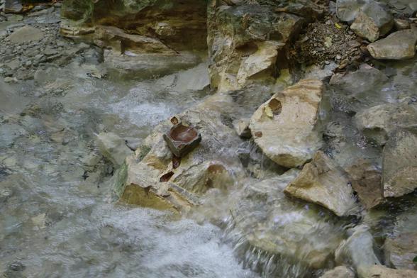The image shows a close-up of a small, clear stream flowing over jagged rocks