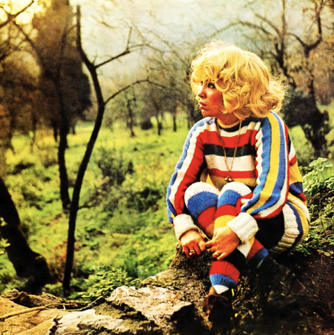 photo of a young woman sitting in the woods, late 70s.