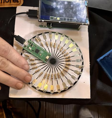 A closer view of the Spoke 26 capacative touch sensor MIDI controller, with a hand in shot 