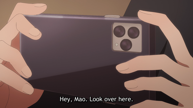 Two hands holding a smart phone in a horizontal orientation. A subtitle says, "Hey, Mao. Look over here."