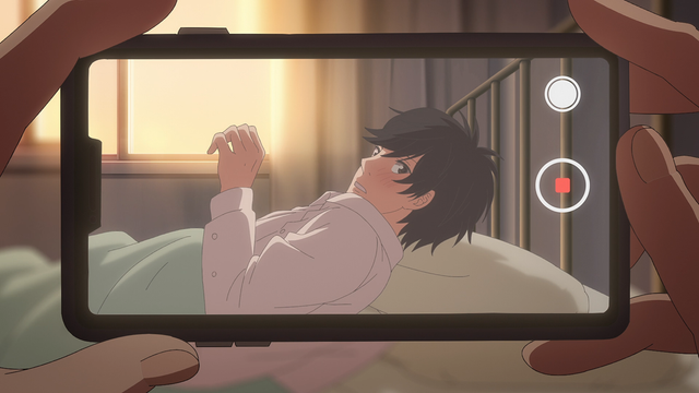 A teenage boy (Mao) turning his head while laying down in a nurse's room bed. He's seen through the video app of a phone.