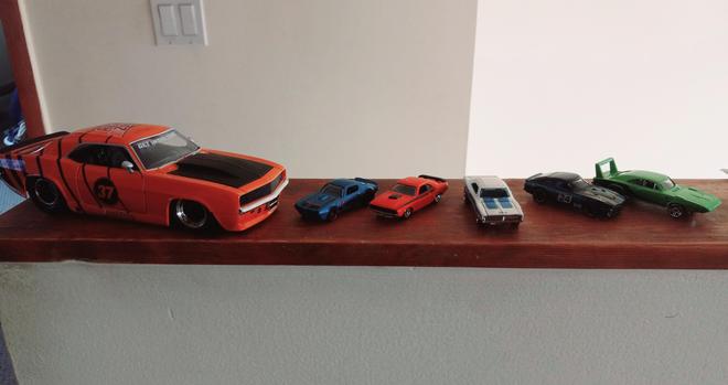 From left to right:

Large orange '69 Chevy Camaro with the AutoZone logo, GET IN THE ZONE, and black stripes 

Blue '73 Pontiac Firebird

Orange '71 Dodge Challenger 

White w/ blue stripes '69 Dodge Charger

Black w/ blue/gold stripes Nissan Datsun 240Z 

Lime green '69 Dodge Charger

All purchased at Autozone while I worked there as a delivery driver (save for the white Charger, which was a gift).
