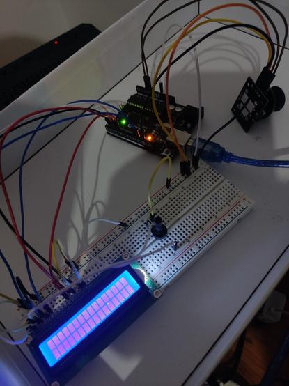 Foto of a circuit where a arduino uno board connects to a lcd display and a joystick through some jumpers and a reusable solderlees breadboard.
