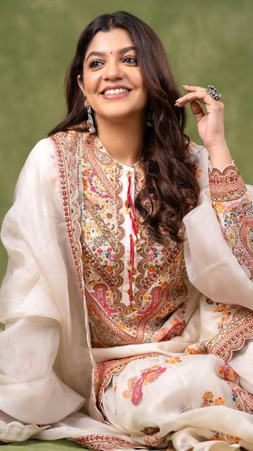 In an exquisite off-white Anarkali suit, Aparna Balamurali redefines elegance and grace. The intricate embroidery and fine detailing of the Anarkali highlight her sophisticated fashion sense, making her look effortlessly stunning. Perfect for any traditional event, this ensemble showcases Aparna's ability to blend classic style with modern trends. Discover the beauty of ethnic wear through Aparna's elegant look and get inspired by her timeless fashion statement.