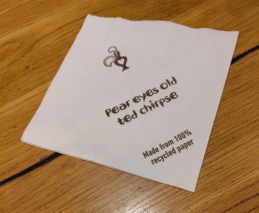 A napkin from Nandos. It says "pear eyes old ted chirpse"

Also it is made from 100% recycled paper