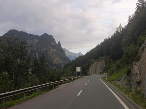 Blick durch die Finstermünz mit dramatischen Bergen und einer Strasse, welche sich dadurch windet. Die Stimmung ist Sommerlich leicht unheimlich, wie vor einem Gewitter.