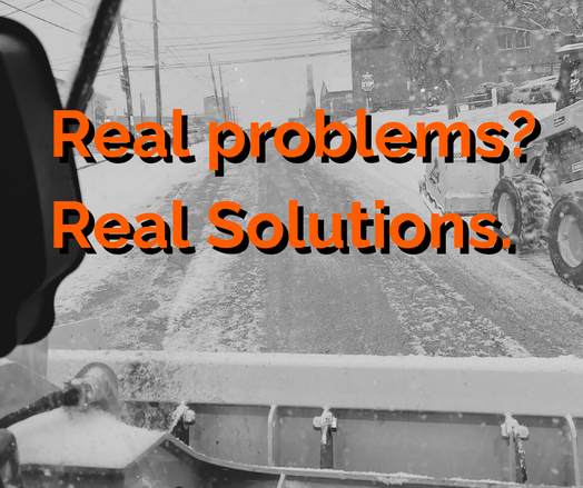 Snowy street scene with a snowplow clearing the road, viewed from the driver's perspective. Overlaid text reads, 'Real problems? Real Solutions.' in bold orange letters.