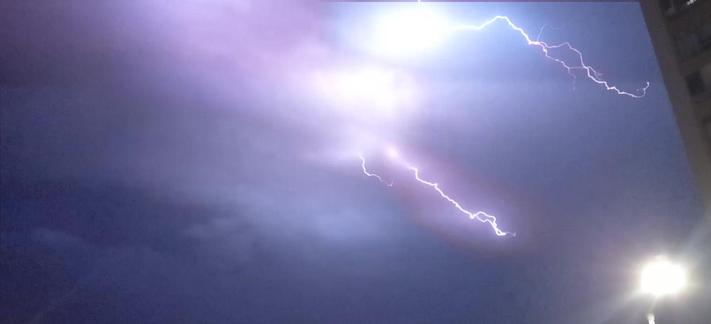 A stack of videoframes showing a lightning in a night sky. The lightning strikes from left to right in two bolts, with some colour differences between them: the bottom one is reddish, the top one is blueish.