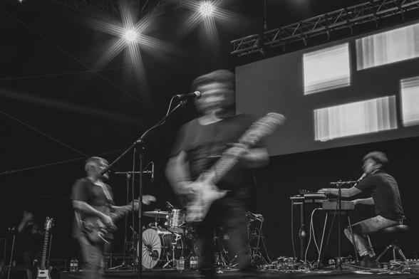 Fotografía en blanco y negro donde se ve una banda tocando con ligero movimiento y desenfoque de los músicos.