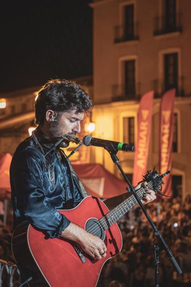 Se puede ver al cantante de Siloé con guitarra y armónica preparado delante del micro para empezar a cantar.