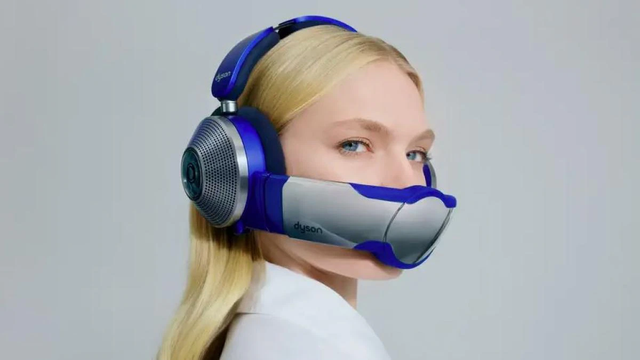 Commercial image of a young, good-looking woman (blond, long hair, blue eyes, as white as white can be) wearing Dyson's ludicrous Zone headphones. Over-ear headphones with bulky earpads (because the vacuuming motor is in there) and a clip-on nose and mouth guard, supposed to supply you with clean air. Too bad a) it isn't a closed system, so you get a mix of clean and regular air, b) it fucking impedes your front view, c) it's as heavy as all capital sins, and d) it blows air to your eyes, drying them. Great job, Dyson!