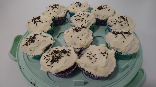 A picture of 11 chocolate cupcakes with icing and chocolate sprinkles.