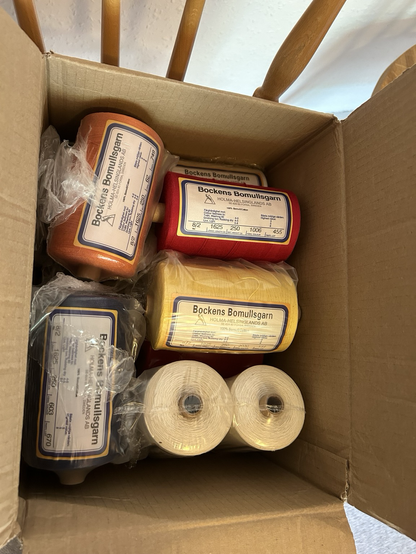A cardbox full of cones of different colours of 8/2 cotton weaving yarn