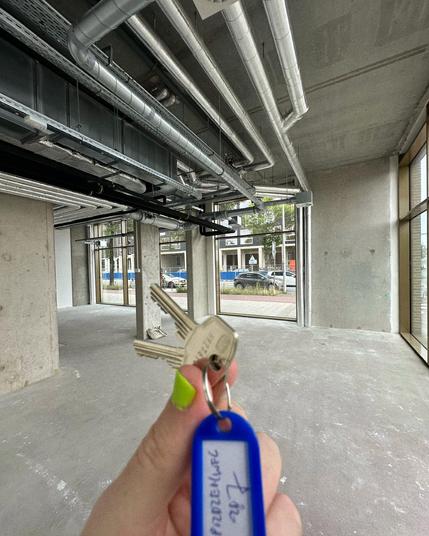 noko's new studio space. big, empty space with tall windows, concrete walls, ceiling and floors. in the foreground, keys held up.