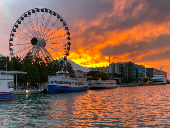 Sunrise at Navy Pier in Chicago. 

Giant ferris wheel in the background, boats on Lake Michigan in the foreground, and clouds ablaze in the golden sunlight at dawn — almost looks like fire that's reaching from the ground to the sky