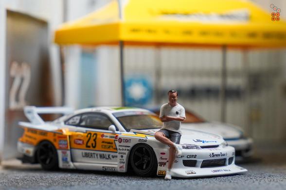 A guy sit on Nissan S15 Silvia No.23, 2022 Goodwood Festival of Speed by MINI GT in 1:64 scale with 1:64 figure on AREA 164