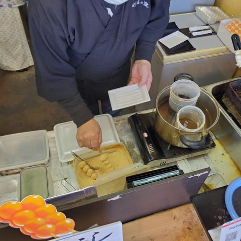 Dipping freshly fried dango in kinako powder.
