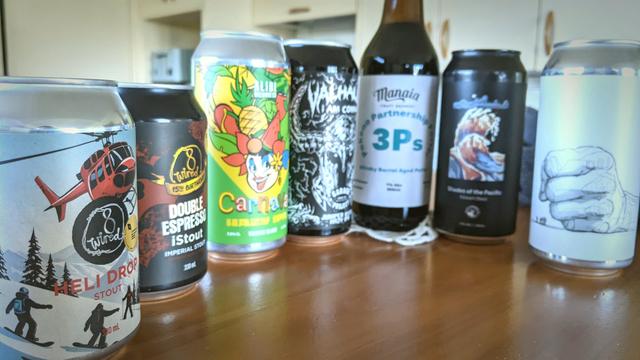 Line-up of 7 craft beers from NZ North Island breweries. From left to right: description of each one in toot above;  2x 330ml cans, 2x 440ml cans, 1x 500ml bottle then 2x 440ml cans.