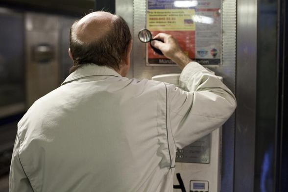 middle-aged friendly: photograph of a balding man trying to read a notice using a magnifying glass. Photo attribution: Flickr user philippeleroyer