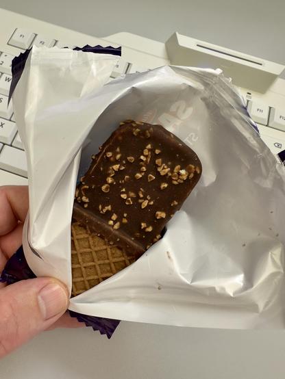 Ein Eis in der geöffneten Verpackung vor einer Tastatur.
