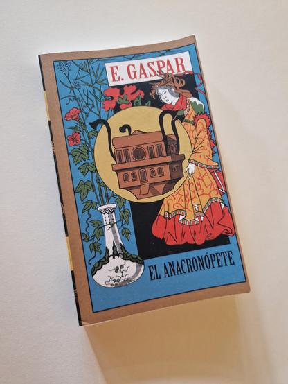 **Alt Text in English:** The image shows a book cover featuring colorful artwork. The title is "El Anacronópete" and the author's name is "E. Gaspar." The design includes an illustrated scene with decorative elements and vibrant colors. The text on the image is slightly distorted, reading "E. GASRAR" and "LANACRONOPETE."

**Alt Text in Spanish:** La imagen muestra una portada de libro con un arte colorido. El título es "El Anacronópete" y el nombre del autor es "E. Gaspar." El diseño incluye una escena ilustrada con elementos decorativos y colores vibrantes. El texto en la imagen está ligeramente distorsionado, leyendo "E. GASRAR" y "LANACRONOPETE."