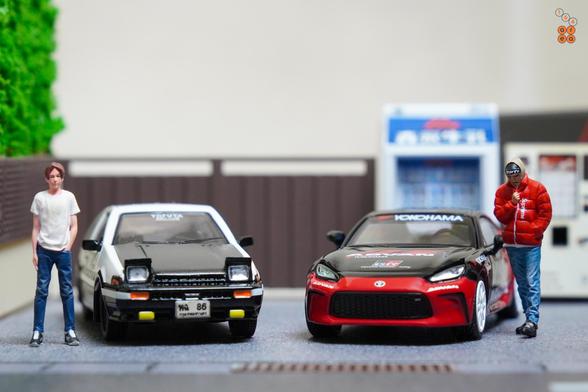 Takumi Fujiwara and a guy in red suit with Toyota 86 Trueno by Time Micro and Toyota GR86 Advan livery by Pop Race in 1:64 scale with 1:64 figure on AREA 164