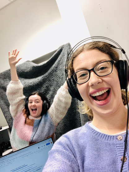 Two women smiling in a podcast studio.