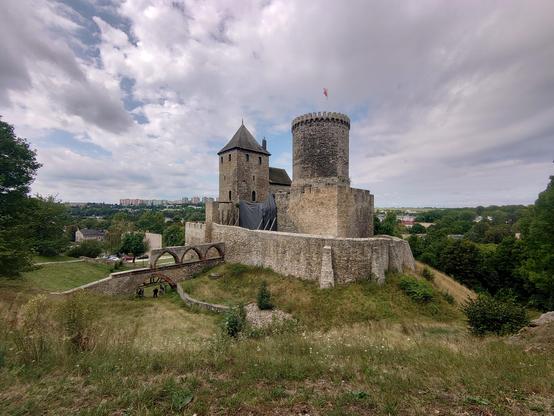 A pair of towers surrounded by a lower wall, and with a ditch in front.