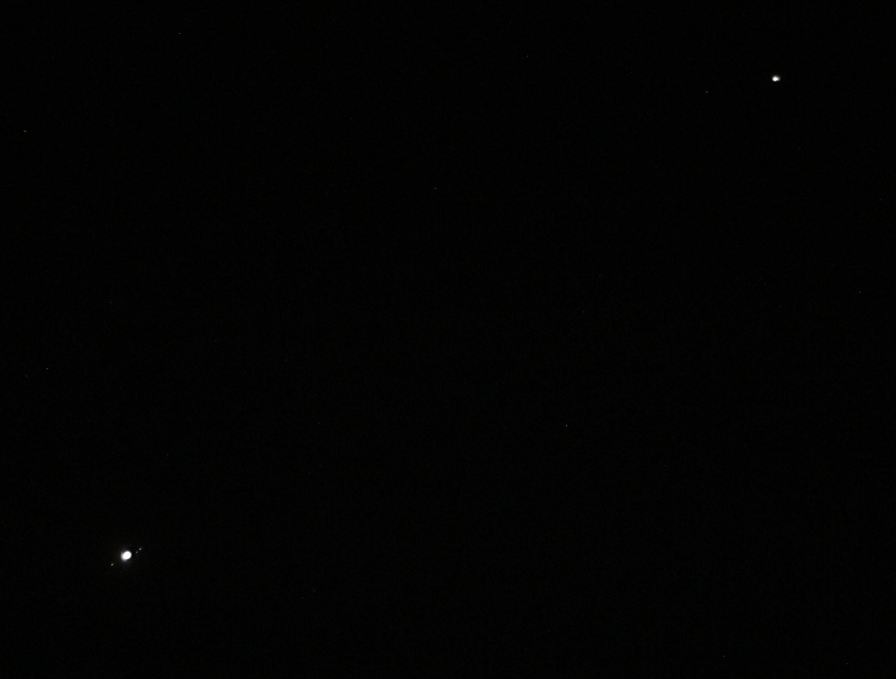 Planet Jupiter with moons dots at lower left corner. Planet Mars at upper right corner. 